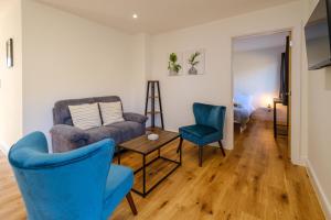 a living room with blue chairs and a couch at Three Tuns - Garden Suite 3 in Wickham Market