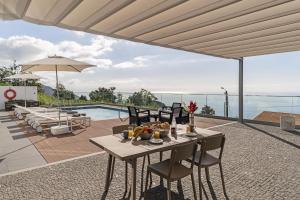 einen Tisch und Stühle auf einer Terrasse mit Pool in der Unterkunft Stunning Funchal Villa - 3 Bedrooms - Vila da Portada - Panoramic Sea Views - Recently Refurbished in Funchal