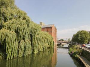 a weeping willow tree over a river with a bridge at The Coach House in Tewkesbury