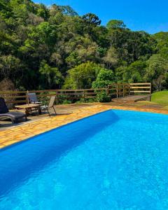 a large blue swimming pool next to a wooden deck at Pousada Olivier da Montanha - Recanto das Águas in Santo Antônio do Pinhal