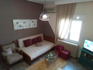 a living room with a couch and a chair and a television at Marosrooms in Tríkala