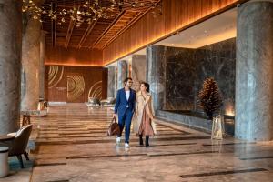 una copia di una coppia che cammina nella hall di un hotel di Hyatt Regency Dehradun Resort and Spa a Dehradun