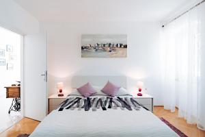 - une chambre blanche avec un grand lit et des oreillers violets dans l'établissement Guest House Sakarun, à Veli Rat