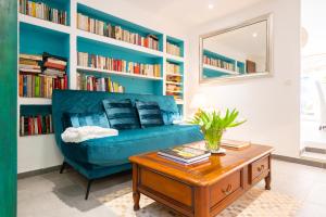 a blue couch in a living room with bookshelves at Appartement de caractère Le Camélia, 56m², dans propriété au calme avec piscine by le Mas de Louise et Sacha in Solliès-Toucas
