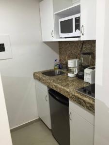 a small kitchen with a sink and a microwave at Ocean View Room 1202near The Clubs in Cancún
