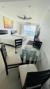 een slaapkamer met 2 bedden en een glazen tafel en stoelen bij Ocean View Room 1202near The Clubs in Cancun