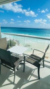 een tafel en een stoel op een balkon met uitzicht op het strand bij Ocean View Room 1202near The Clubs in Cancun