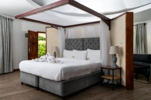 a bedroom with a canopy bed with a teddy bear on it at Poa Place Resort & Hotel - Where Nature Meets Comfort Eldoret in Eldoret