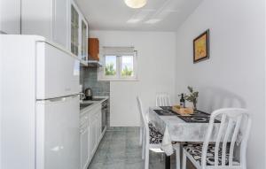 a kitchen with a white refrigerator and a table with chairs at 2 Bedroom Beautiful Apartment In Pinezici in Pinezici