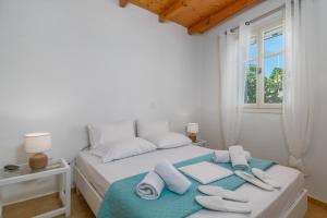 Un dormitorio blanco con una cama con toallas. en Lina and Babis' Home, en Adamas