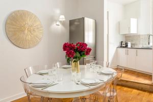 een witte tafel met stoelen en een vaas met rode bloemen bij Cosy 3 Bedroom 1 bathroom - Champs Elysees in Parijs