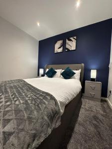 a bedroom with a large bed with a blue wall at Stylish 2bed house in birmingham in Birmingham