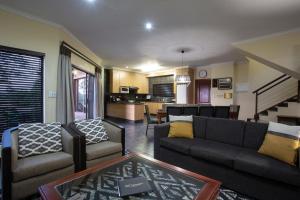 ein Wohnzimmer mit Sofa, Stühlen und einem Tisch in der Unterkunft Hippo Hills Lodge Ngwenya in Marloth Park