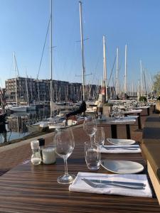 a wooden table with wine glasses on top of a marina at Stylish 3-bdrm apt. w/ terraces next to the beach in The Hague