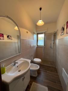 ein Badezimmer mit einem Waschbecken, einem WC und einem Spiegel in der Unterkunft Casa vacanze La Via del Mare in Scanzano
