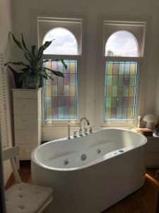 een badkamer met een wit bad en glas-in-loodramen bij Stylish 3-bdrm apt. w/ terraces next to the beach in Den Haag