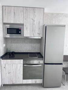 a kitchen with a white refrigerator and a microwave at GATU Villa Camarote con vistas al mar in Cádiz