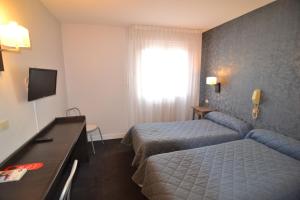 a hotel room with two beds and a television at Brit Hotel Cahors - Le Valentré in Cahors