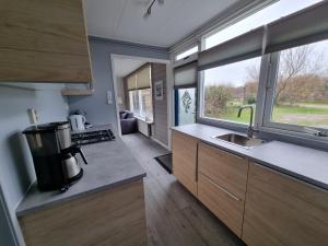 uma pequena cozinha com um lavatório e uma janela em Zilt Zand em De Koog