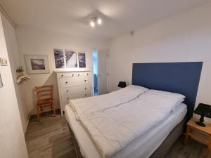 een slaapkamer met een groot bed en een stoel bij Zilt Zand in De Koog