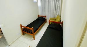 een kleine kamer met 2 bedden en een stoel bij Mega Flat na Praia da Ocian - Praia Grande in Praia Grande