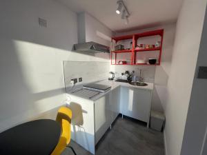 a small kitchen with red cabinets and a sink at Modern studio apartment; 10min walk to town & quay in Exeter