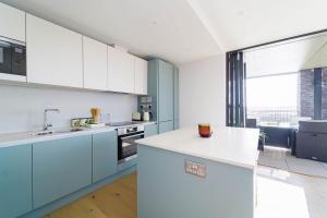 a kitchen with blue cabinets and white counters at Beach Pad in Hayle