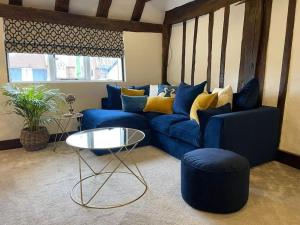 un soggiorno con divano blu e tavolo di Rural Country Suites - Judge's Lodge a East Grinstead