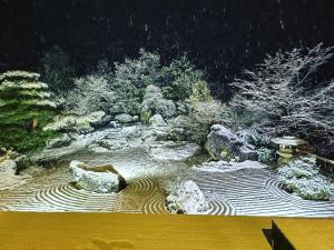 箱根町にあるOnsen & Garden -Asante Inn-の雪中の岩や木々の庭