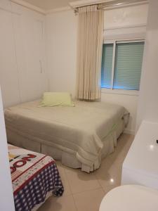 1 dormitorio con 1 cama en una habitación con ventana en Cobertura bombinhas beira mar, en Bombinhas