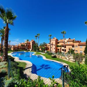 - une piscine dans un complexe avec des palmiers et des bâtiments dans l'établissement Penthouse in Reserva de Marbella, à Marbella