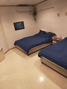 a bedroom with two beds with blue sheets at Cheers チアーズ 離島ﾀｰﾐﾅﾙ歩4分 ﾌﾟﾛｼﾞｪｸﾀｰ有 WiFi無料 ﾀﾞｰﾂ有 無料P1台分付 in Ishigaki Island