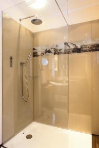 La salle de bains est pourvue d'une douche avec une porte en verre. dans l'établissement Hotel Simonshof, à Wolfsburg