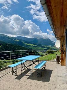 a blue table and two benches on a roof at Pool Villa Savognin in Tinzen