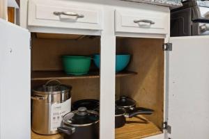 un armario de cocina con ollas y sartenes. en Historic + Pet-Friendly Gem, en Bay City