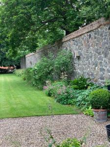 a garden with a stone wall and some plants at Gartnerhuset på Kollerup in Hadsten Stationsby