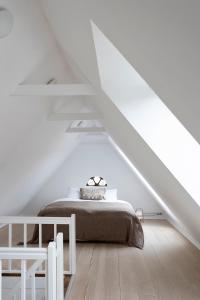a white bedroom with a bed in a attic at Gartnerhuset på Kollerup in Hadsten Stationsby