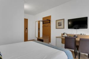 a bedroom with a bed and a desk and a tv at Aurora Hotel at Reykjavik-Keflavik Airport Terminal KEF in Keflav&iacute;k