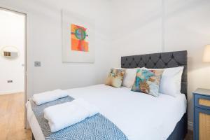 a bedroom with a large white bed with pillows at London Paddington Station Apartments in London