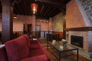 sala de estar con sofá rojo y chimenea en La Hosteria de Castroviejo, en Duruelo de la Sierra