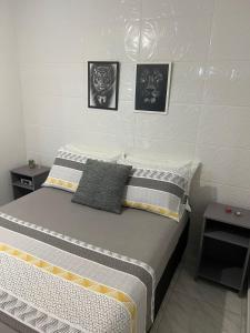 1 cama en un dormitorio con 3 cuadros en la pared en Apartamento Studio com banheiro privativo en São José