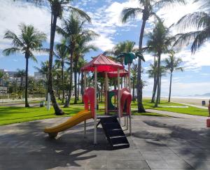 a playground in a park with a slide and palm trees at Excelente Apartamento no Centro de Bertioga in Bertioga