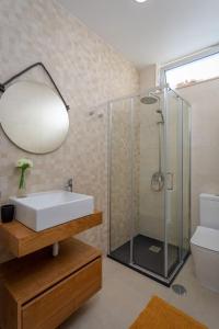 ein Bad mit einem Waschbecken und einer Glasdusche in der Unterkunft Apartamento novo e acolhedor na Praia da Barra in Gafanha da Nazaré