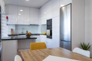 eine Küche mit einem Holztisch und einem Kühlschrank in der Unterkunft Apartamento novo e acolhedor na Praia da Barra in Gafanha da Nazaré