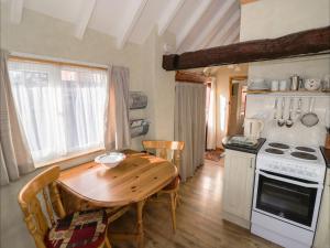 uma cozinha com uma mesa de madeira, uma mesa e um fogão em The Byre em Worcester