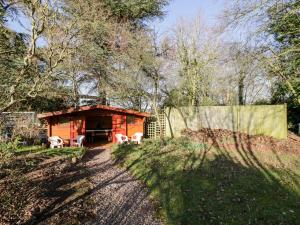 uma pequena cabana com uma mesa e cadeiras na floresta em The Orangery em Worcester