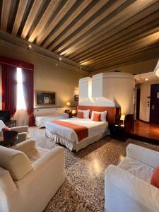 ヴェネツィアにあるルッツィーニ パレス ホテルのベッド2台とソファが備わる広いホテルルームです。
