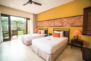two beds in a hotel room with yellow walls at Pandanus Resort in Mui Ne