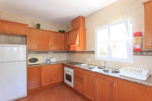 a kitchen with wooden cabinets and a white refrigerator at Villa Toymi in Ciutadella