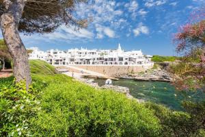 a large white building on a hill next to a river at Villa Toymi in Ciutadella